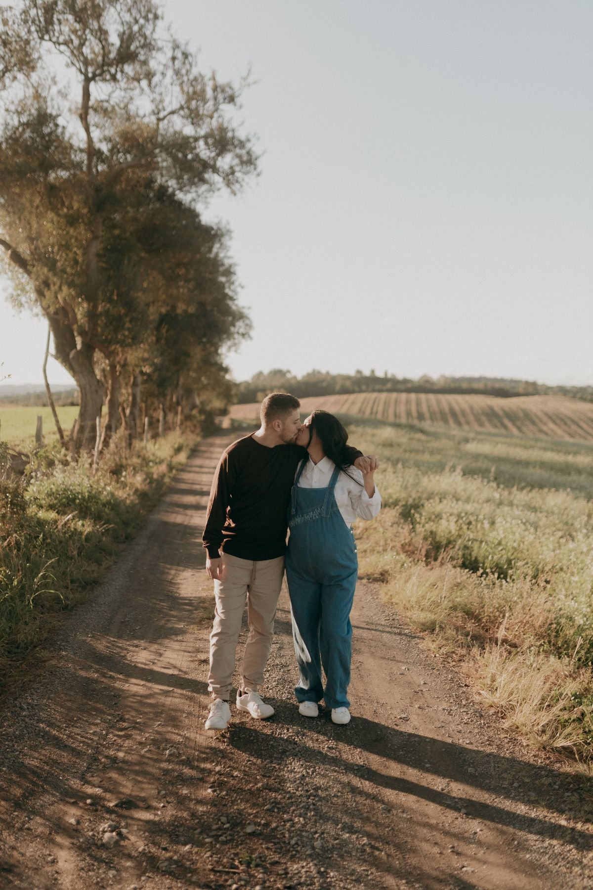 Una pareja comparte un beso durante un paseo por un camino rural